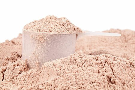 A scoop resting in a mound of pale brown powder